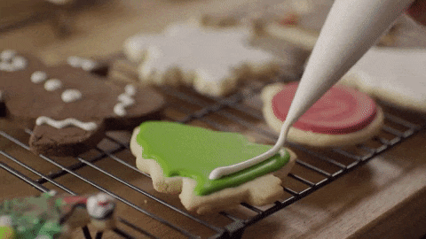 gif of gingerbread cookies and gingerbread tree cookie being decorated
