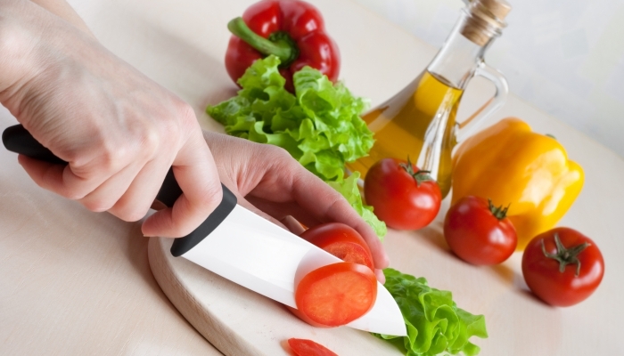 White ceramic knife cutting tomato